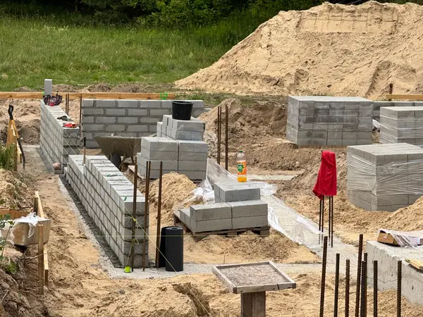 Bloczki fundamentowe w trakcie wznoszenia ścian — prawidłowe wiązanie murarskie, prety zbrojeniowe wystające z ścian